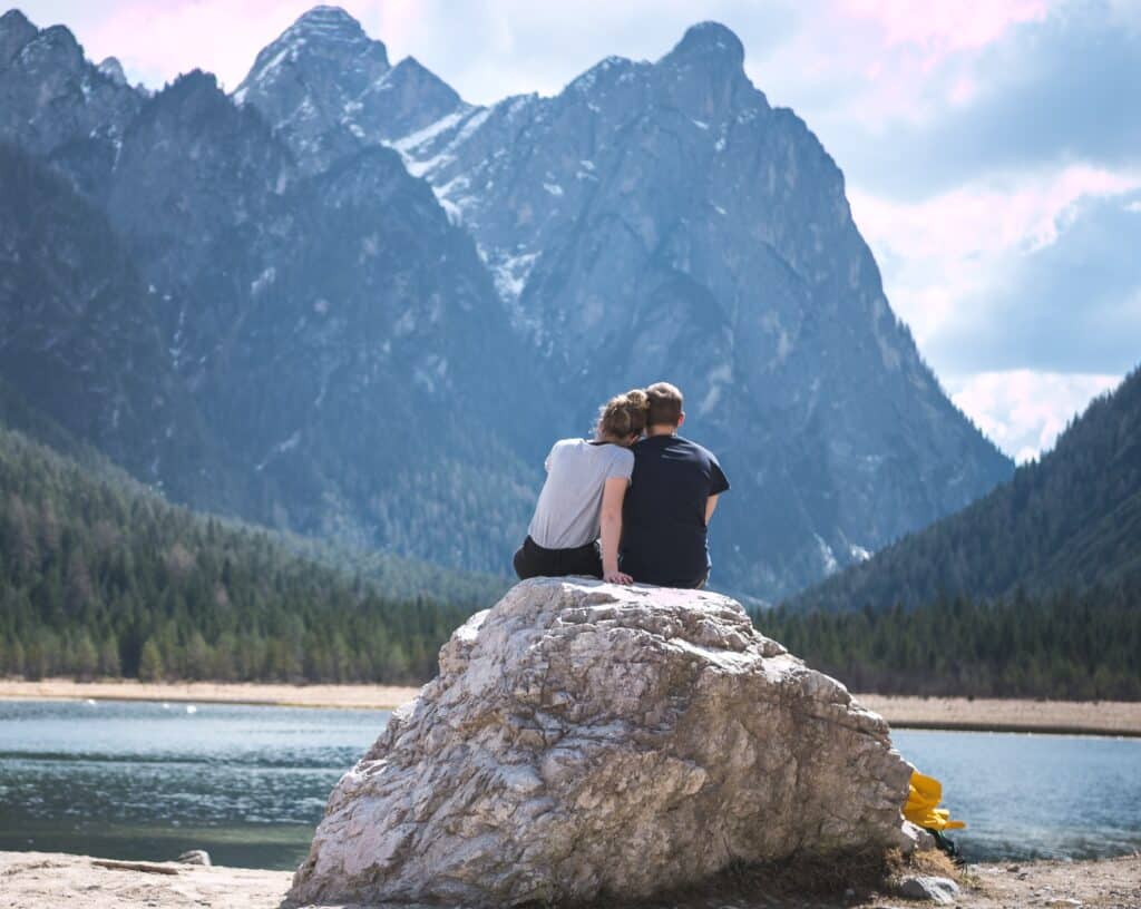 Couple admiring the view from the shore of a lake.